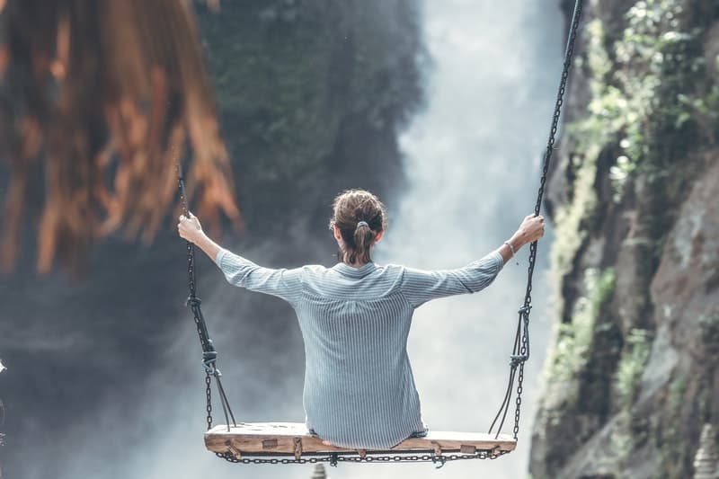woman on a swing over a waterfall