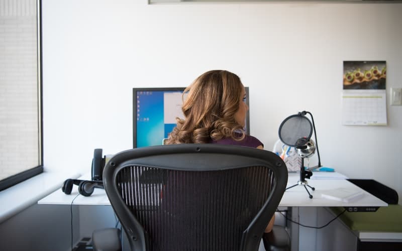 a woman sitting at a desk with podcasting equipment in front of her