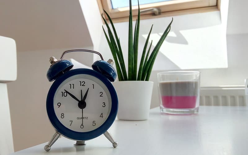 a clock and a plant on a white desk
