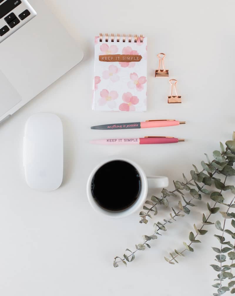 a white desk with coffee, a mouse, and office supplies