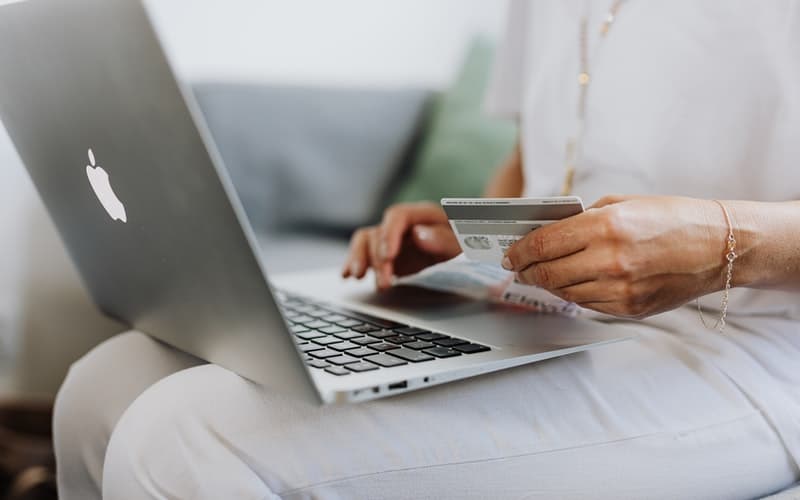 a woman holding a credit card and her laptop