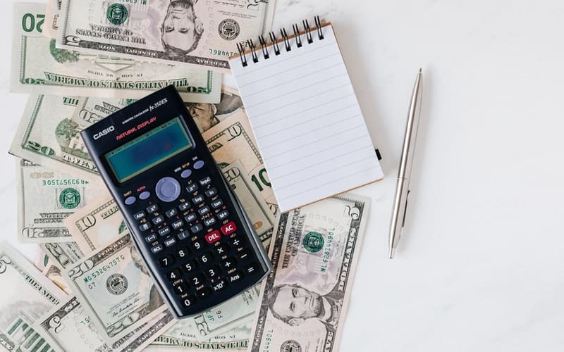 a calculator, pad of paper, and money on a desk