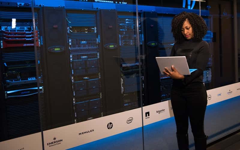 woman holding a laptop near a row of servers