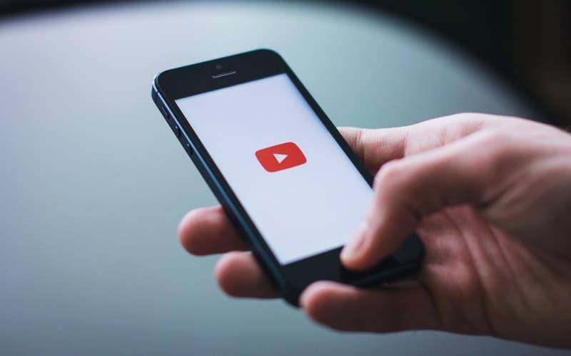 a hand holding a cell phone with a YouTube logo on it