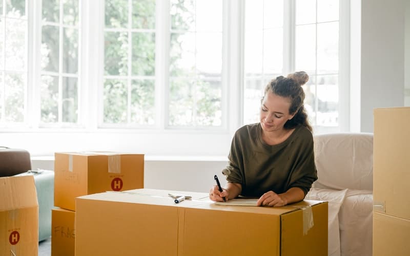 a woman writing on a moving box