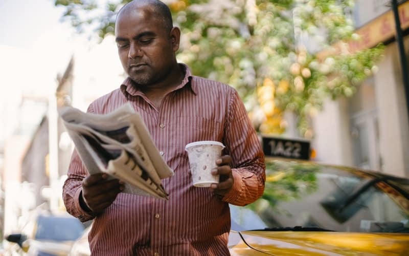 a man reading a newspaper with a cup of coffee