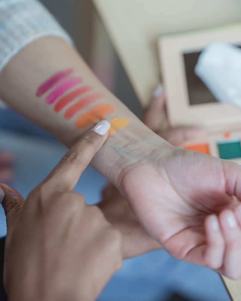 a woman with color swatches of makeup on her arm