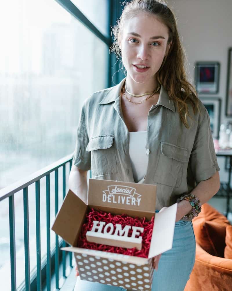 a woman holding a box with a home sign in it