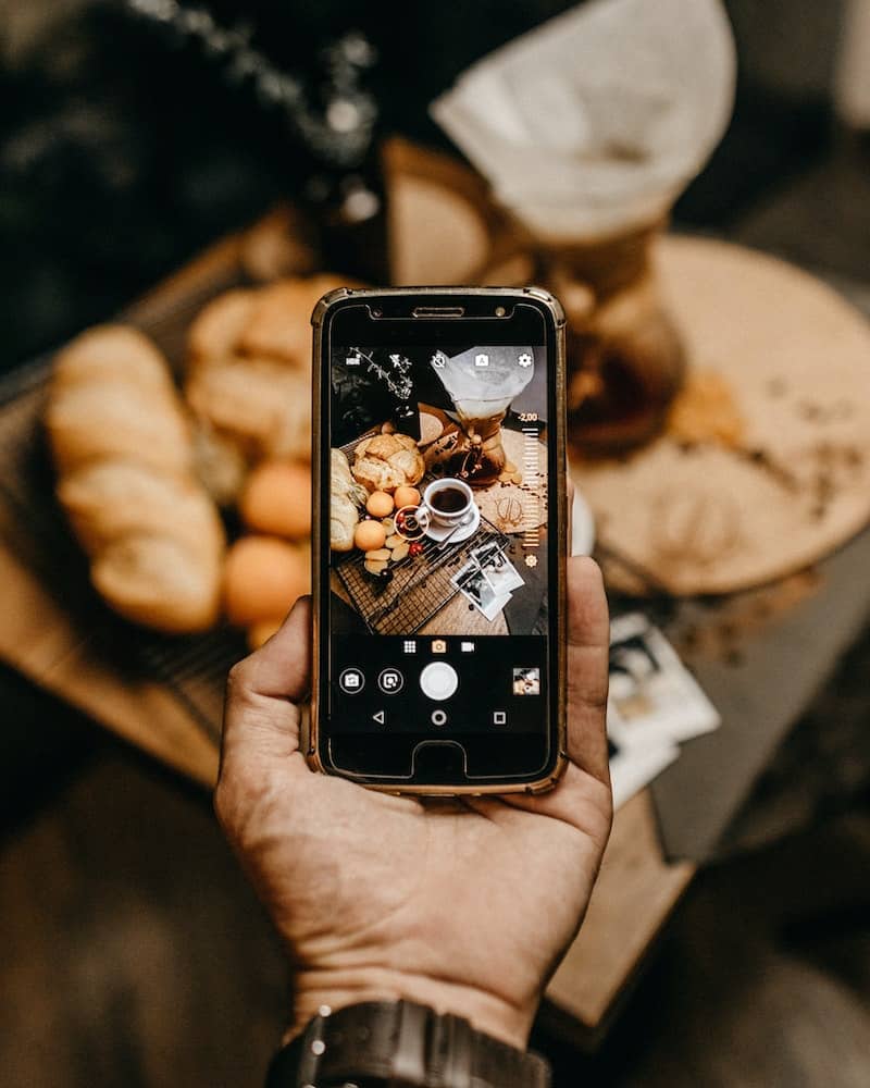 a man using a mobile phone to take a food photograph