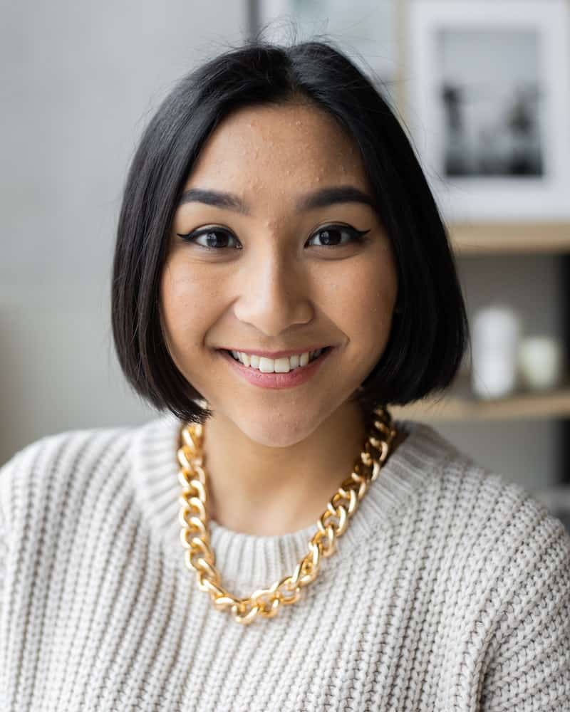 an ethnic woman wearing a gold chain and white sweater