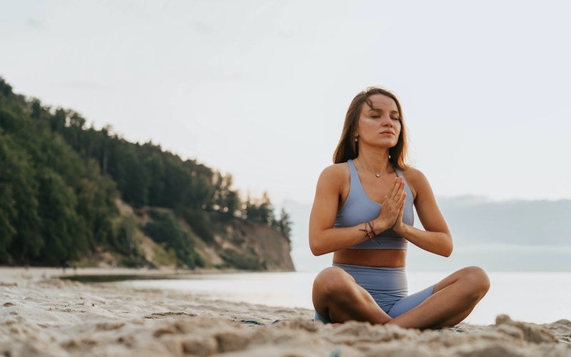 woman sitting in the sand meditating