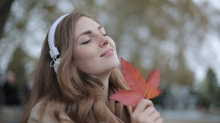 woman wearing headphones holding a fall leaf